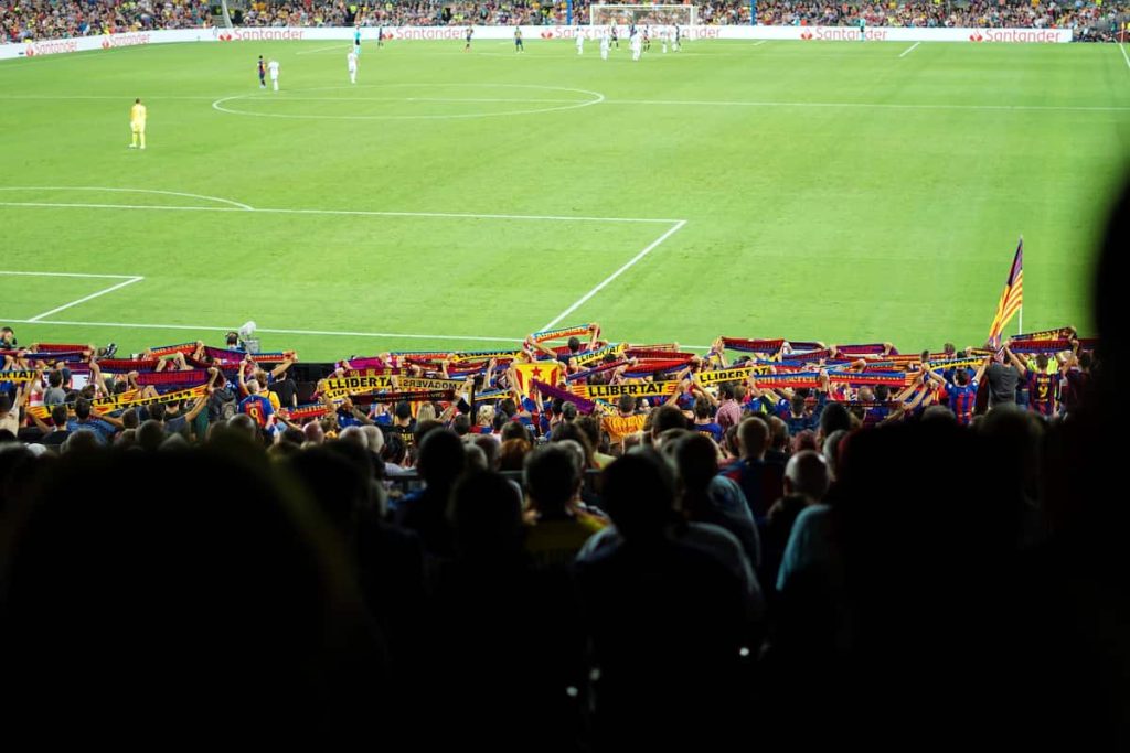 Barcelona fans raising their club scarves during a match.