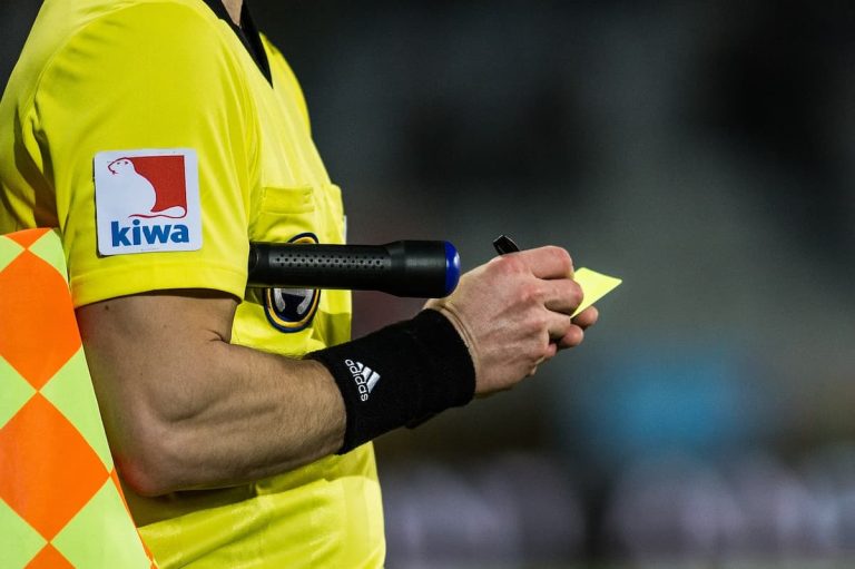 A football official holding a flag and cards.
