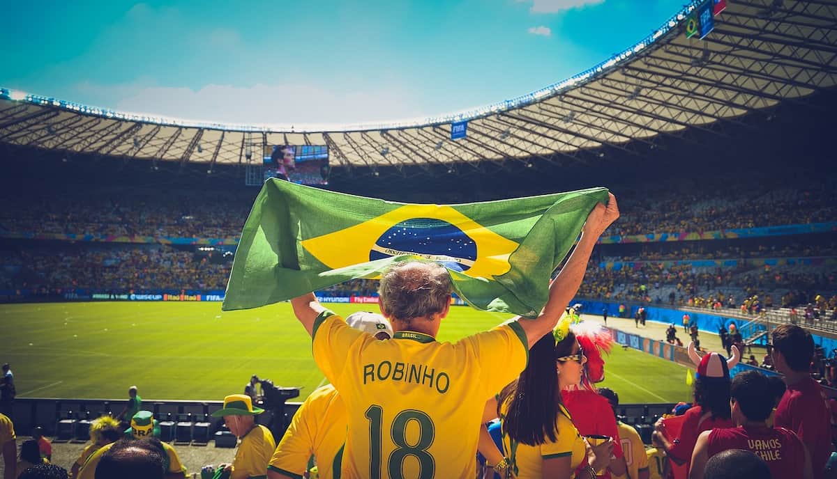 A Brazilian football fan waving a national flag in a football stadium.
