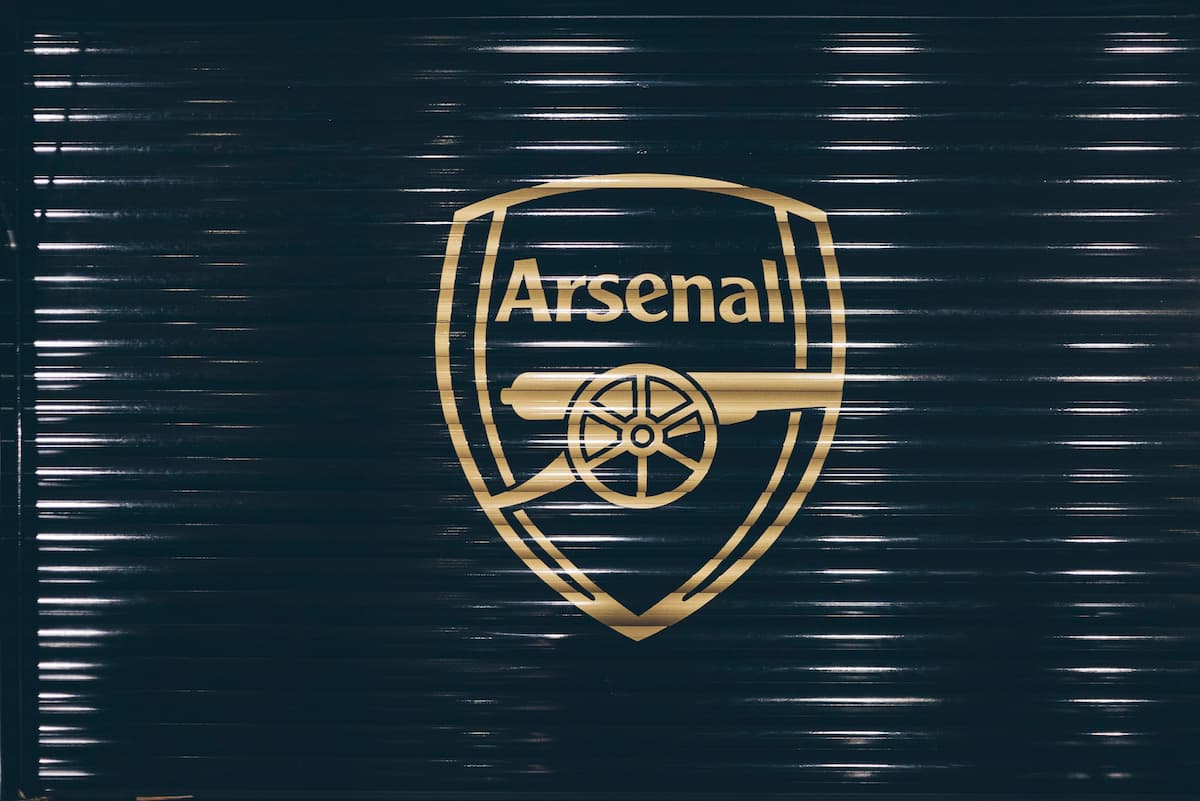 A gold Arsenal FC badge painted on a black metal shutter.